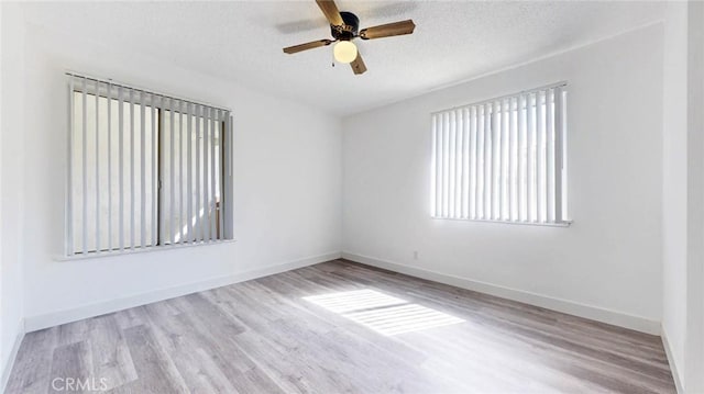 unfurnished room with ceiling fan, a textured ceiling, baseboards, and wood finished floors