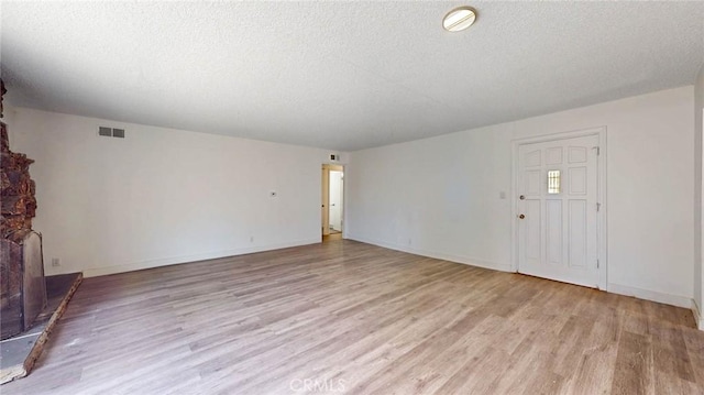 unfurnished living room with light wood-type flooring, baseboards, visible vents, and a textured ceiling