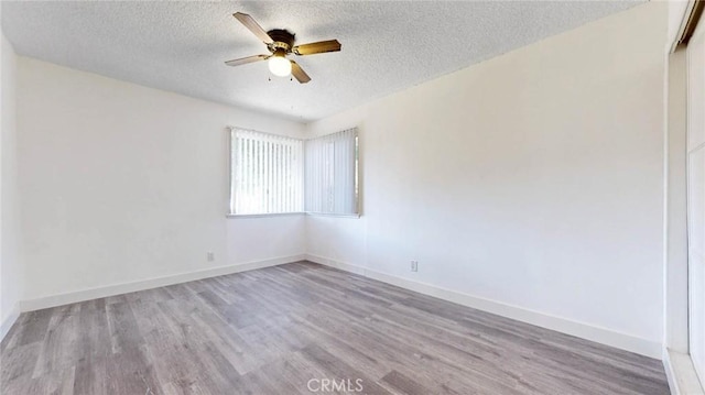 empty room featuring a ceiling fan, a textured ceiling, baseboards, and wood finished floors