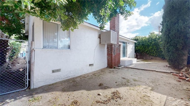 view of side of home with crawl space, a chimney, fence, and stucco siding