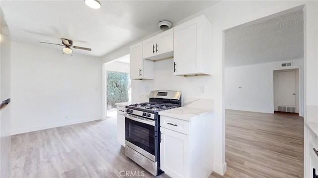 kitchen featuring light stone countertops, stainless steel gas range oven, visible vents, and ceiling fan