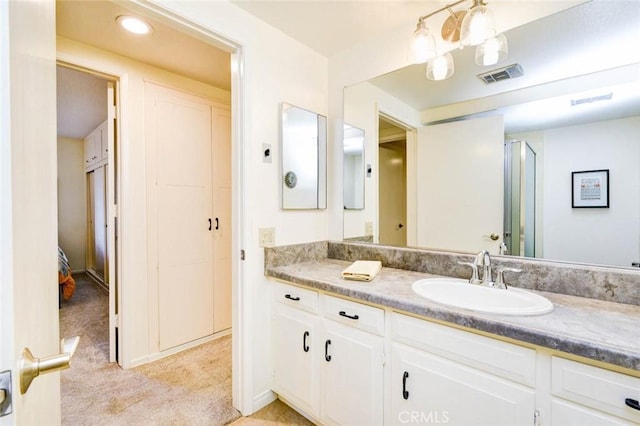 bathroom with a shower with door, visible vents, and vanity