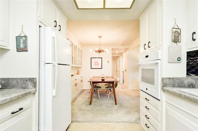 kitchen with white appliances, light countertops, a notable chandelier, and light colored carpet