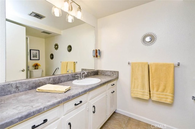 bathroom with visible vents, toilet, vanity, baseboards, and tile patterned floors