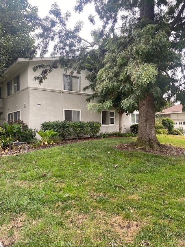 view of side of property with a lawn and stucco siding