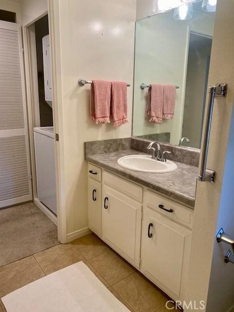 bathroom featuring tile patterned floors, vanity, and stacked washer and clothes dryer