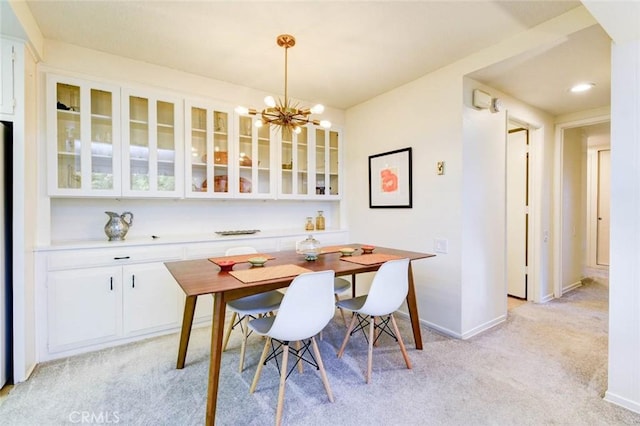 dining space with baseboards, a chandelier, and light colored carpet