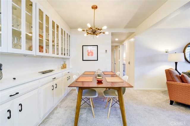 dining area with a chandelier, baseboards, and light colored carpet