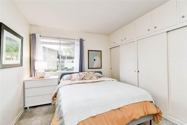 bedroom with light colored carpet, baseboards, and two closets