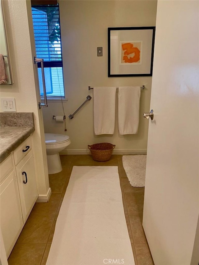 bathroom featuring tile patterned flooring, baseboards, vanity, and toilet