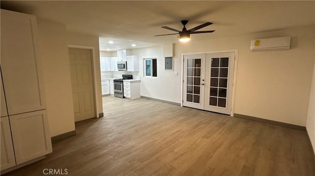 unfurnished room featuring light wood-type flooring, french doors, a wall unit AC, and electric panel