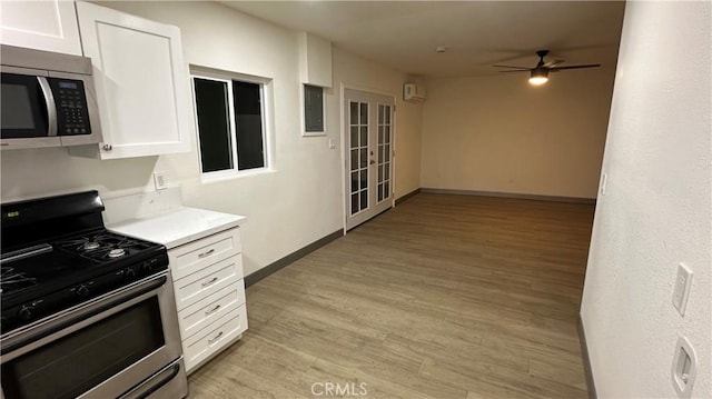 kitchen with electric panel, white cabinets, a ceiling fan, stainless steel appliances, and light wood-type flooring