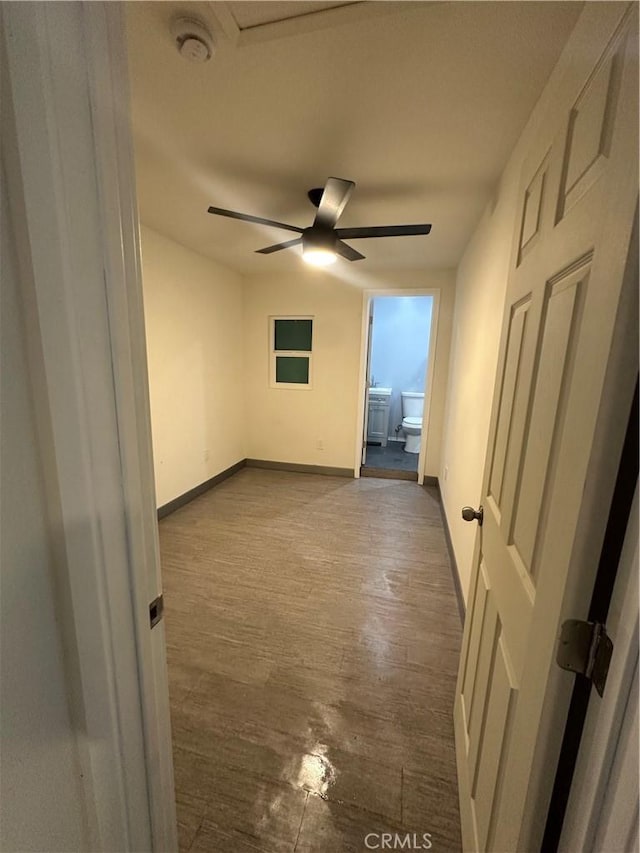 spare room with baseboards, dark wood finished floors, and a ceiling fan