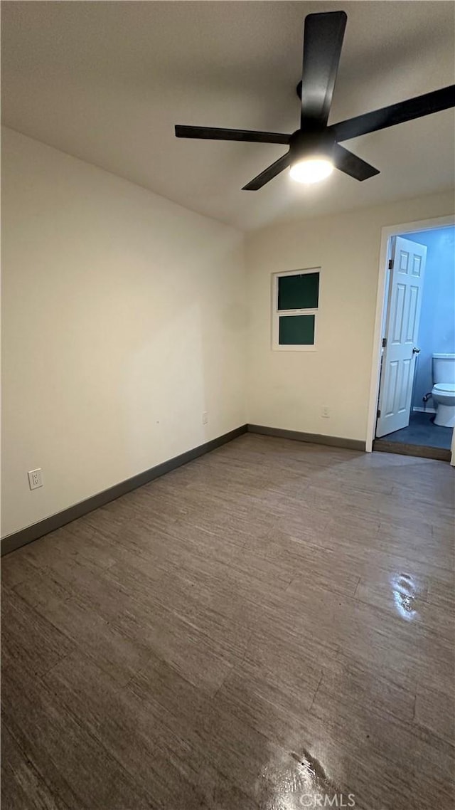 spare room featuring dark wood finished floors, a ceiling fan, and baseboards