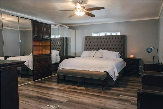 bedroom featuring dark wood-type flooring, ornamental molding, and a ceiling fan