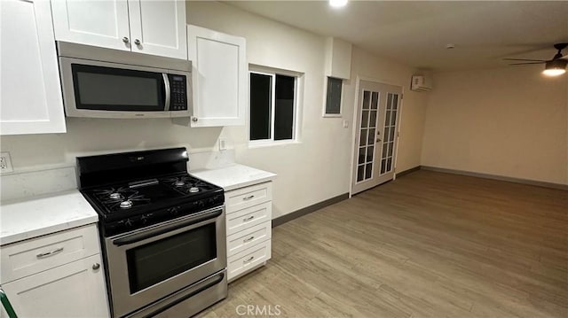 kitchen featuring white cabinets, ceiling fan, light wood-style floors, and stainless steel appliances
