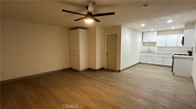 kitchen with light wood-style flooring, light countertops, baseboards, and ceiling fan