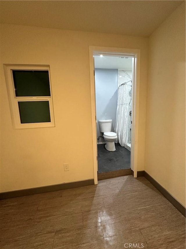 bathroom featuring curtained shower, baseboards, and toilet