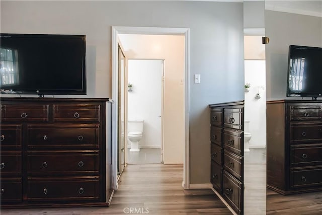 bedroom with baseboards, connected bathroom, and wood finished floors
