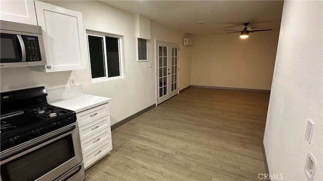 kitchen featuring white cabinets, baseboards, light wood-type flooring, a ceiling fan, and stainless steel appliances