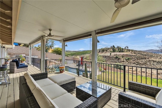 deck featuring a ceiling fan, a yard, and an outdoor living space