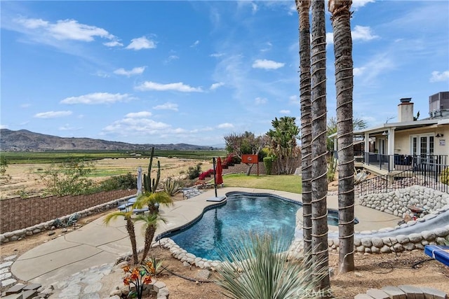 view of swimming pool featuring a patio area, fence, a mountain view, and a fenced in pool