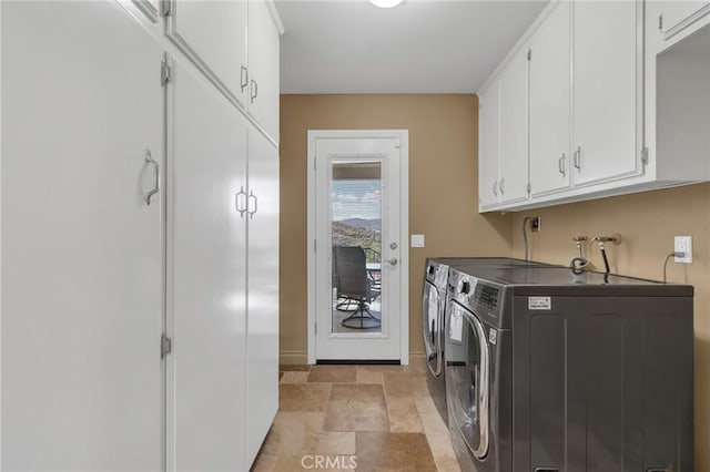 laundry area featuring stone finish floor, cabinet space, baseboards, and washing machine and clothes dryer