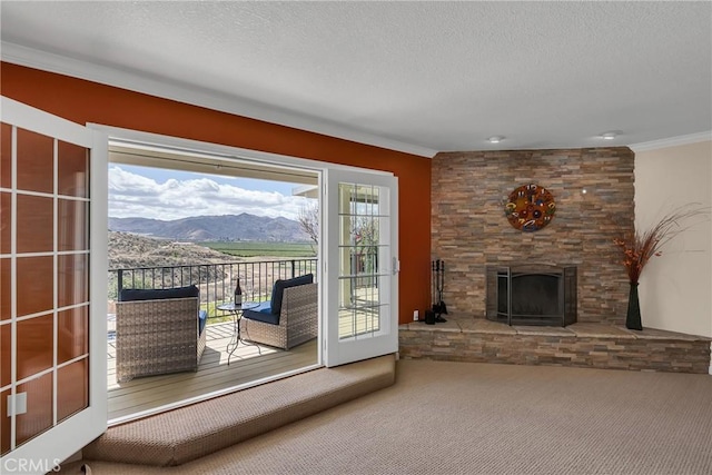 entryway featuring crown molding, a fireplace, a textured ceiling, and a mountain view