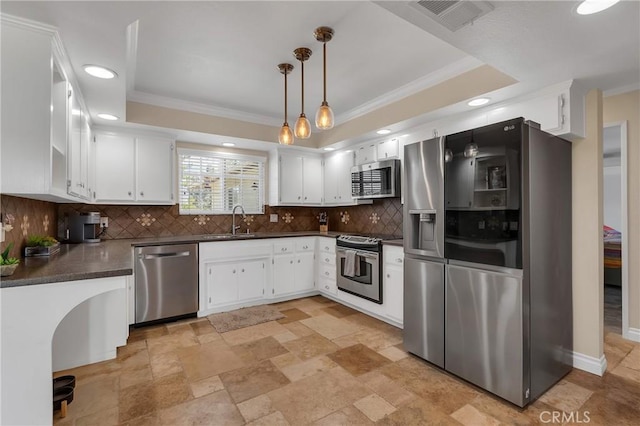 kitchen featuring stainless steel appliances, a sink, visible vents, a tray ceiling, and dark countertops