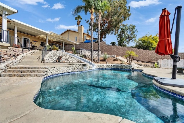 view of pool featuring a fenced in pool, a patio, a water slide, a fenced backyard, and stairs