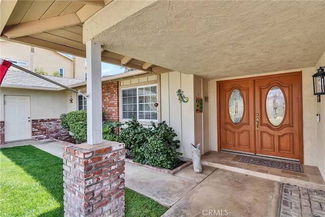 entrance to property featuring stucco siding, a porch, a lawn, and brick siding