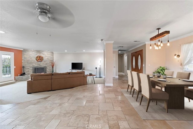 living area with crown molding, stone tile floors, a stone fireplace, a textured ceiling, and baseboards