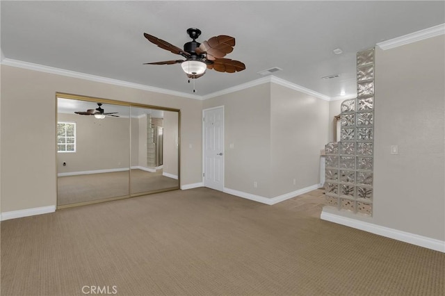 unfurnished living room featuring carpet floors, ceiling fan, baseboards, and crown molding