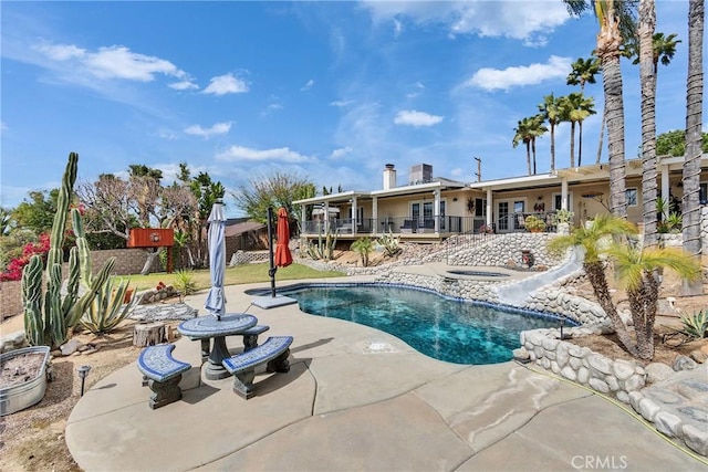 pool with a patio area, a hot tub, and a water slide