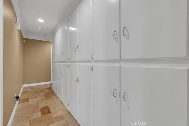 corridor featuring stone finish flooring, attic access, and baseboards