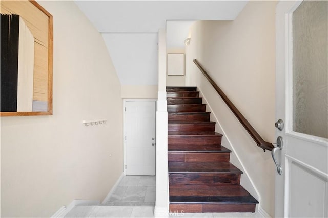 stairway featuring baseboards and vaulted ceiling