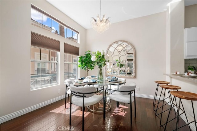 dining room with dark wood-style flooring, a notable chandelier, and baseboards