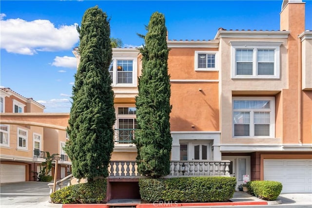 townhome / multi-family property with a garage, driveway, and stucco siding