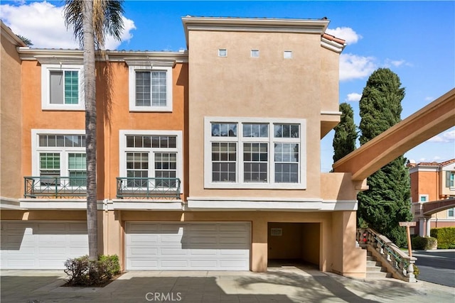 view of front facade with an attached garage, driveway, and stucco siding