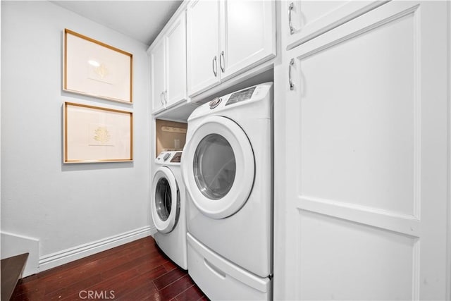 laundry room featuring dark wood-style floors, washer and dryer, cabinet space, and baseboards