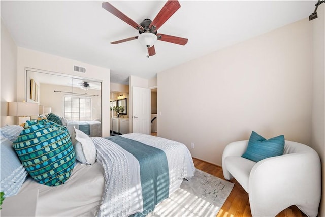 bedroom featuring a ceiling fan, visible vents, and wood finished floors