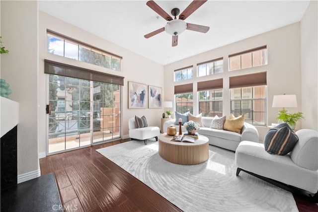 living area featuring ceiling fan, a fireplace, baseboards, and hardwood / wood-style flooring