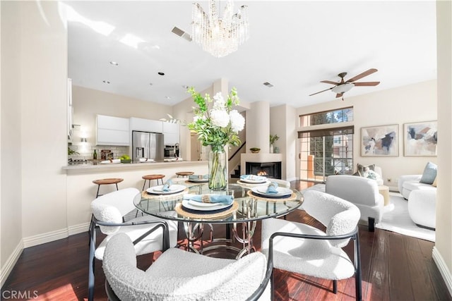 dining room with a lit fireplace, dark wood finished floors, visible vents, and baseboards