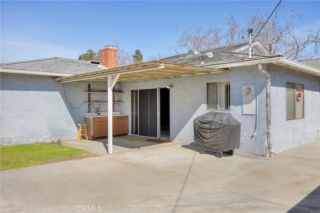 rear view of house with a patio area and stucco siding