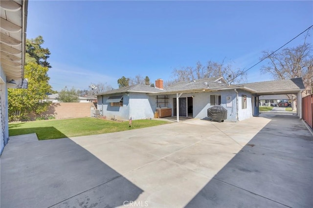 rear view of house featuring a yard, driveway, a carport, and fence