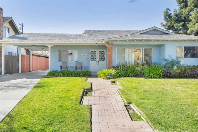 view of front facade with driveway, a carport, a front yard, and stucco siding