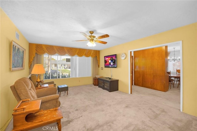 living area featuring carpet floors, visible vents, and ceiling fan with notable chandelier