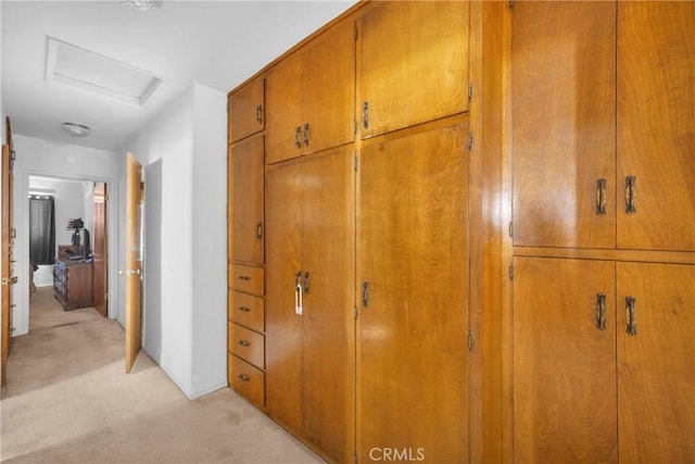 corridor featuring attic access and light colored carpet