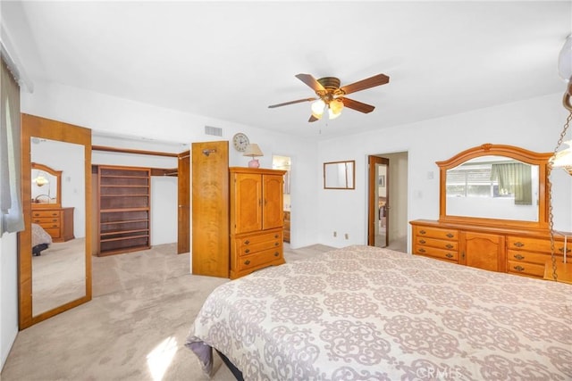 bedroom with light carpet, a ceiling fan, visible vents, and a closet