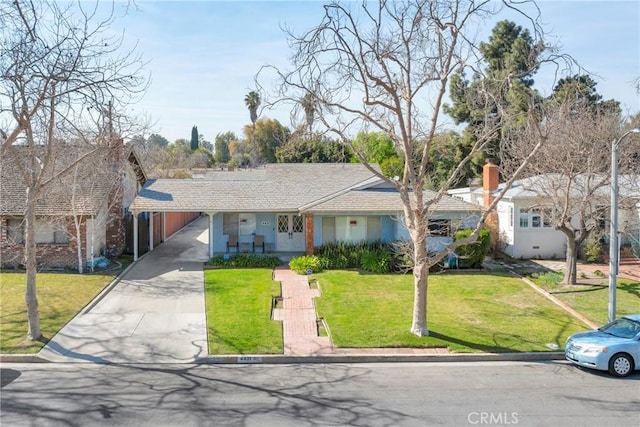 ranch-style home featuring driveway, an attached carport, and a front yard